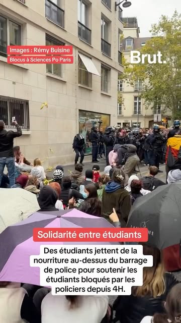 Des étudiants jettent de la nourriture au-dessus du barrage de police pour soutenir les étudiants bloqués par les policiers depuis 4H.