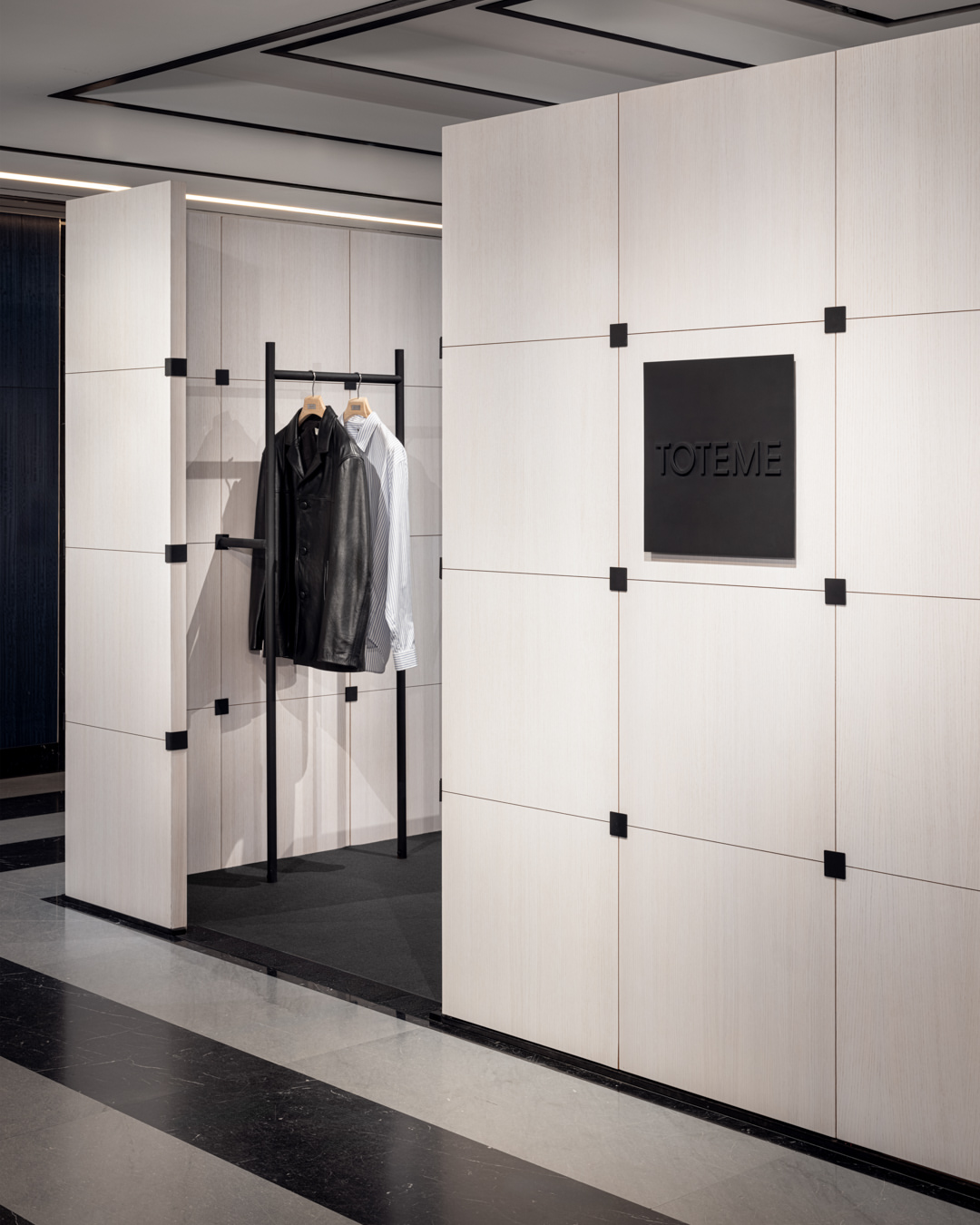 Presenting the inaugural TOTEME men’s collection at Harrods, London. White-stained oak panelling, blackened steel, and exposed structural details create a restrained, graphic interior that reflects the house’s emphasi…