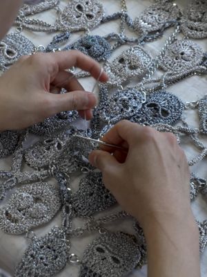 In the Atelier Look 29 Intricate metallic skull motifs crocheted by hand, embellished with crystal and pearl details. Sculptural archival headpiece in silver with electroformed roses and garnet beading, by master jewe…